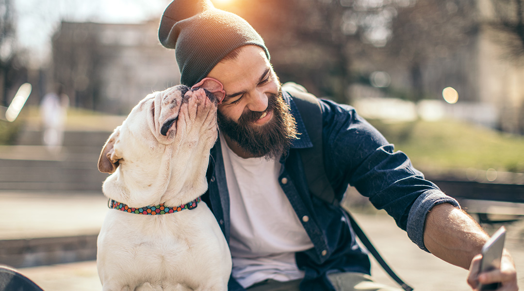 A man trying to take a selfie with his dog that is licking his forehead